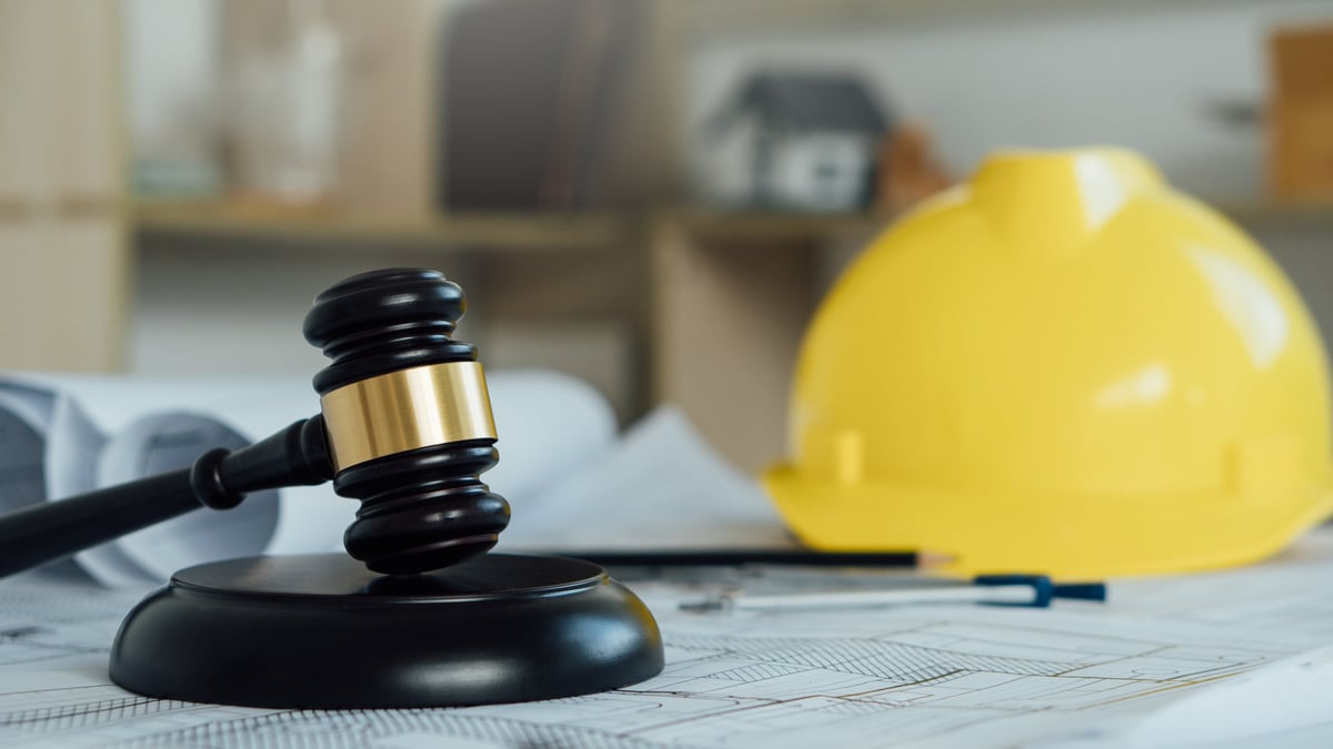 Gavel with safety helmet and blueprint representing compliant professional services